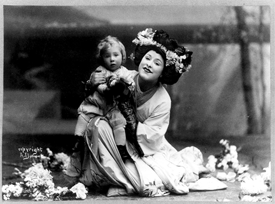 Geraldine Farrar, 1882-1967, full length, kneeling child on knee, facing slightly left, in Madame Butterfly.