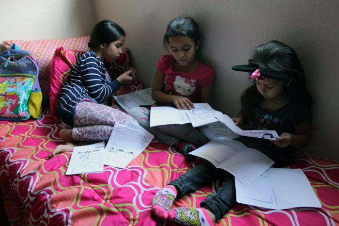 Arwa (izquierda), Marwa (centro) y Rawan (derecha), hacen la tarea en una tarde reciente. Las hermanas llegaron a Turlock, California, en febrero, luego de huir de la guerra en Siria. Crédito: Monica Campbell. Utilizado con autorización de PRI/Global Voices.
