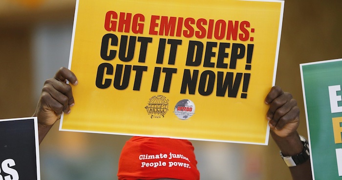 Un hombre sostiene un póster en el que se puede leer "Gases de efecto invernadero, córtalos en profundidad, córtalos ahora" en la cumbre del clima en Le Bourget a las afueras de París (Francia). Foto: EFE.