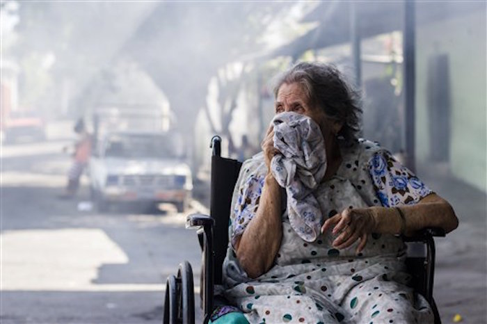 Carmen Chicas Mejía, de 82 años, se cubre el rostro mientras trabajadores municipales fumigan su casa para combatir el mosquito portador del virus del zika en el barrio de San Judas en San Salvador el 26 de enero del 2016. El zika se ensaña con las mujeres embarazadas, que dan a luz bebés con problemas, y les plantea un gran dilema: abortar o no en una región donde el aborto está a menudo penado. Foto: AP