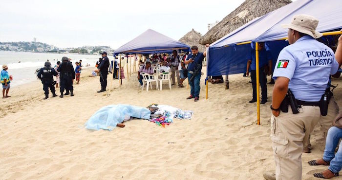 Agentes de diversas corporaciones policiacas rodean el cuerpo del vendedor ambulante de ropa asesinado ayer a plena luz del día en la playa Carabalí. Tras cometer el crimen, el agresor habría huido en una moto acuática, según testigos . Foto: El Sur
