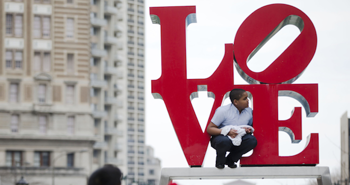 Un joven sube a la escultura de Robert Indiana en la Plaza JFK. Foto: Archivo/AP