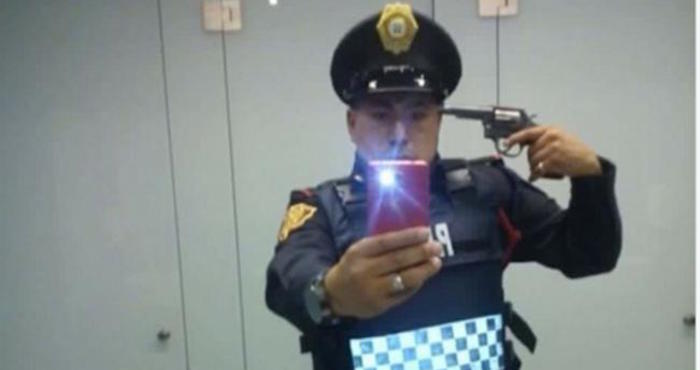 Héctor Mauro Ramos, fue suspendido de sus funciones, luego de tomarse una fotografía apuntándose con su arma en la cabeza. Foto: Twitter