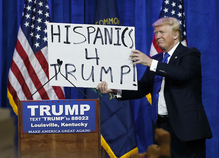 El precandidato presidencial republicano Donald Trump sostiene un cartel que dice "Hispanos con Trump" y que cargaba un espectador durante un mitin el martes 1 de marzo de 2016 en Louisville, Kentucky. Foto: AP.