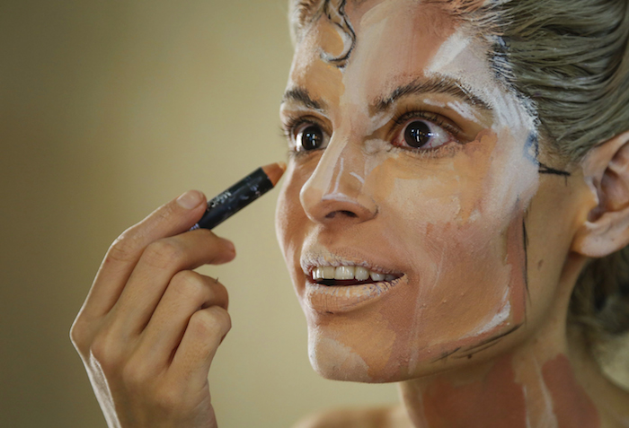 En esta foto del 19 de marzo del 2016, Kay Pike usa pintura y látex para transformarse en Superman, en su casa en Calgary, Canadá. La artista de 28 años se transforma en distintos personajes para un público en Internet. (Jeff McIntosh/The Canadian Press vía AP)