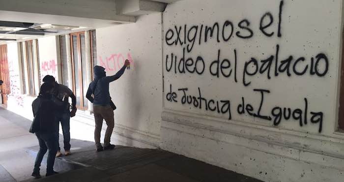 En la imagen, un grupo de jóvenes realiza una pinta en la que se lee "exigimos el video del palacio de Justicia de Iguala". Foto: Jesús Guerrero, El Sur.