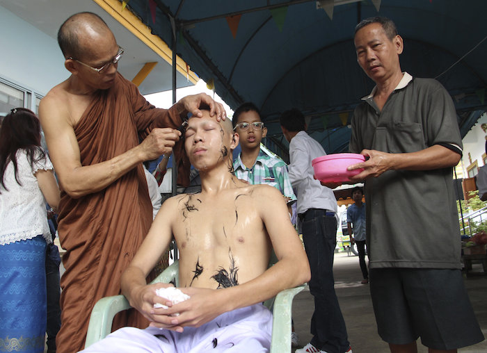 Un monje rasura las cejas de Abhisit Jiwwichai durante la ceremonia de ordenación como monje budista. Foto EFE