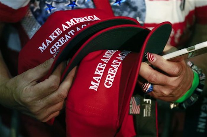 Esta foto tomada el 2 de junio del 2016 muestra a una mujer sosteniendo gorros para que el virtual nominado a la presidencia por el Partido Republicano, Donald Trump, los firme durante un mitin en San JosÈ, California. Los gorros con el lema ìMake America Great Againî, de la campaÒa de Trump, tienen una etiqueta que dice que son "hechos en Estados Unidos" pero eso no es siempre cierto, de acuerdo con un an·lisis de The Associated Press. (Foto AP /Jae C. Hong)