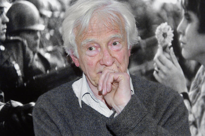 Flores contra ballonetas. Marc Riboud frente a su famosa fotografía de la manifestación contra la guerra de Vietnam, durante una retrospectiva de su obra en Paris, en 2004. Foto: LaOpinión