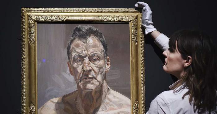 Una mujer sostiene la obra "Reflejo", autorretrato de Lucian Freud. Foto: Efe