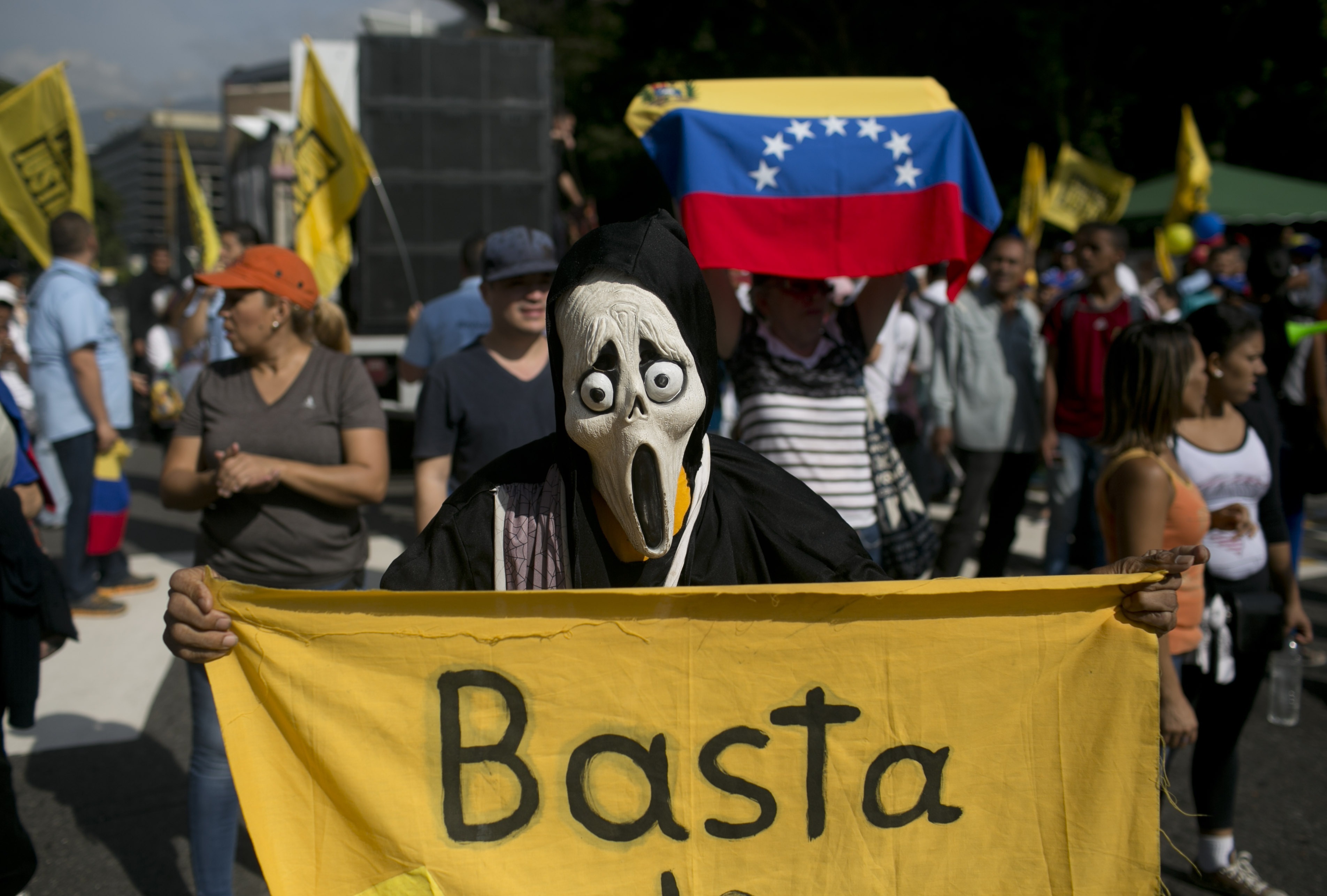 Un manifestante enmascarado sostiene un cartel que dice Basta y rinde protesta contra el presidente Nicolás Maduro en Caracas, Venezuela. Foto: AP
