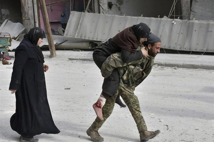 Fotografía facilitada por la agencia siria SANA que muestra a un soldado sirio que traslada a hombros a una mujer herida después de que el gobierno tomara el control de la zona en Alepo (Siria) ayer, 12 de diciembre. Foto: EFE.