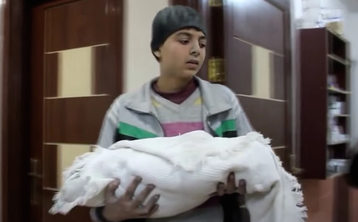 Mahmoud sostiene en brazos a su hermanito de un mes de vida, quien falleció durante los bombardeos en Alepo. Foto: Captura de pantalla.