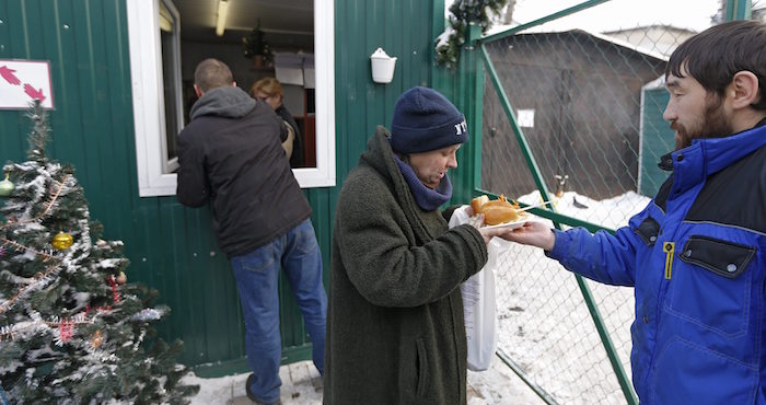 Una mujer recibe un plato de comida cerca de un refugio en Moscú, Rusia. Foto: EFE.