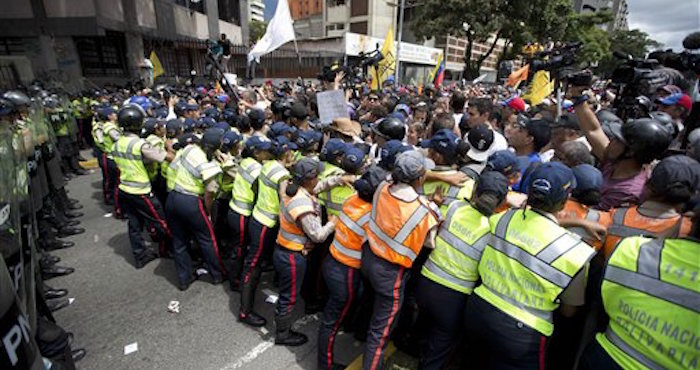 Oficiales de la PolicÌa Nacional Bolivariana forman una cadena humana que bloquea a los manifestantes. Foto: Ariana Cubillos/AP.