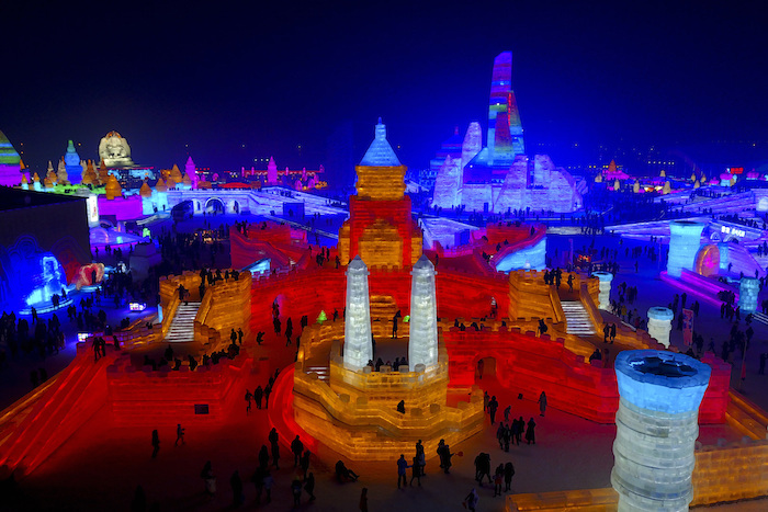 In this Dec. 31, 2016 photo, visitors tours a building structure made from blocks of ice at the Harbin International Ice and Snow festival held in Harbin in northeastern's China's Heilongjiang province. The city of Harbin in China’s frigid northeast is in its final stages of preparation for one of the world’s largest ice and snow festivals, an annual event that last year drew more than a million visitors. (Chinatopix via AP)