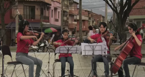 Cuatro miembros de la Red de Escuelas de Música de Medellín tocan parte de “La Tierra del Olvido” desde una de las comunas de Medellín. Captura de pantalla del video disponible en la cuenta de YouTube de Playing for a Change. Foto: GlobalVoices