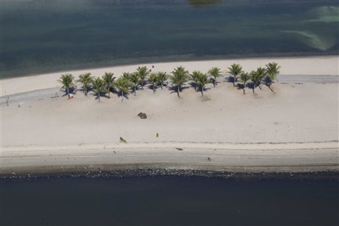 Un lago artificial construido en un suburbio pobre de RÌo de Janeiro (arriba), separado por una estrecha franja de arena de las contaminadas aguas. Foto: AP