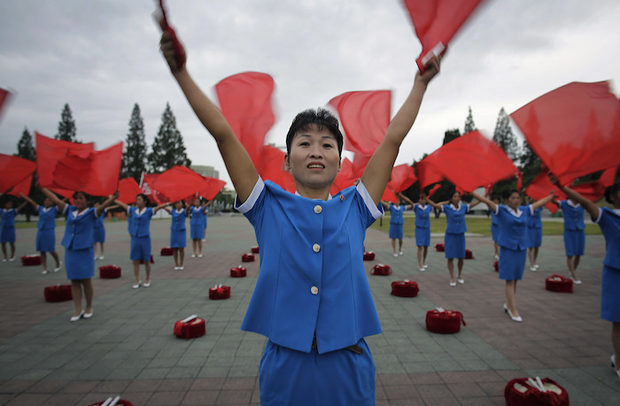 Mujeres norcoreanas ondean banderas saludando a sus compatriotas. Foto: AP