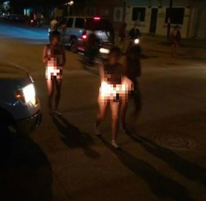En la imagen, las tres mujeres obligadas a caminar desnudas son acompañadas por locatarios. Foto: Especial.