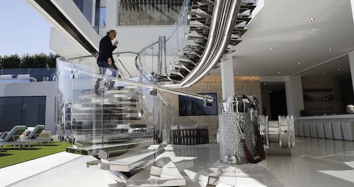 Bruce Makowsky mientras baja por una escalera artesanal de acero y vidrio junto a una escultura enorme de una cámara Leica. Foto: AP