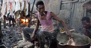 Gesner Sagaille remueve la cabeza de una cabra en una olla de agua hirviendo para retirar el pelo. Foto: AP