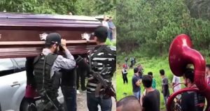 Al ritmo de música banda, se observa a un grupo de hombres armados que cargan el ataúd. Foto: Captura de pantalla, especial.
