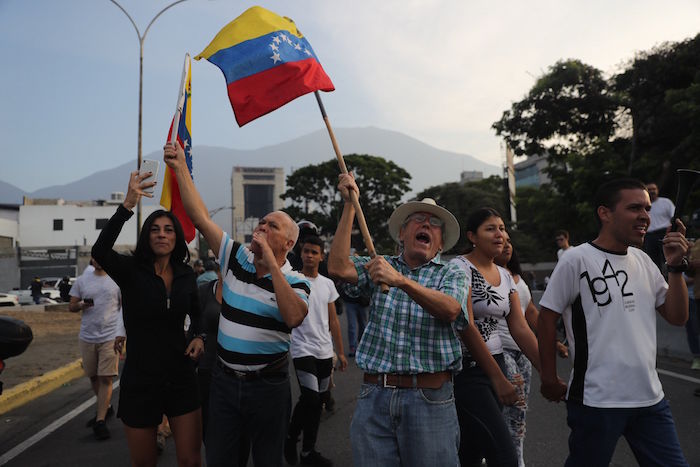 Simpatizantes del Presidente interino Juan Guaidó ondean banderas este martes en la base militar La Carlota. Foto: Miguel Gutiérrez, EFE.