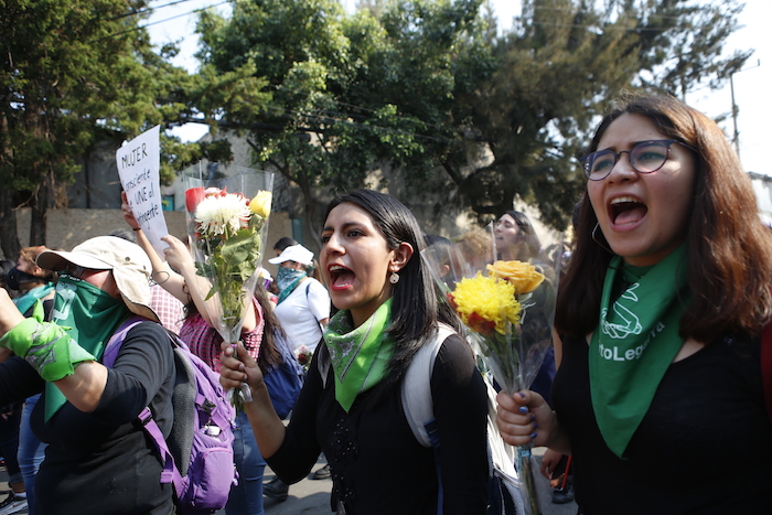 Mujeres lanzan consignas con flores en las manos mieNtras se dirigen al edificio de apartamentos en que Ingrid Escamilla fue asesinada y desollada, en Ciudad de México, el sábado 15 de febrero de 2020. Foto: Ginnette Riquelme, AP