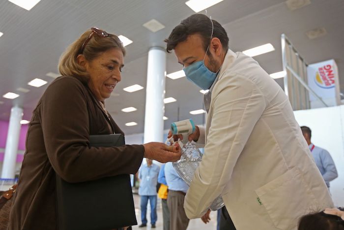 Un hombre pone gel antibacterial en las manos de una mujer, en el aeropuerto de Guadalajara. Foto: Fernando Carranza, Cuartoscuro