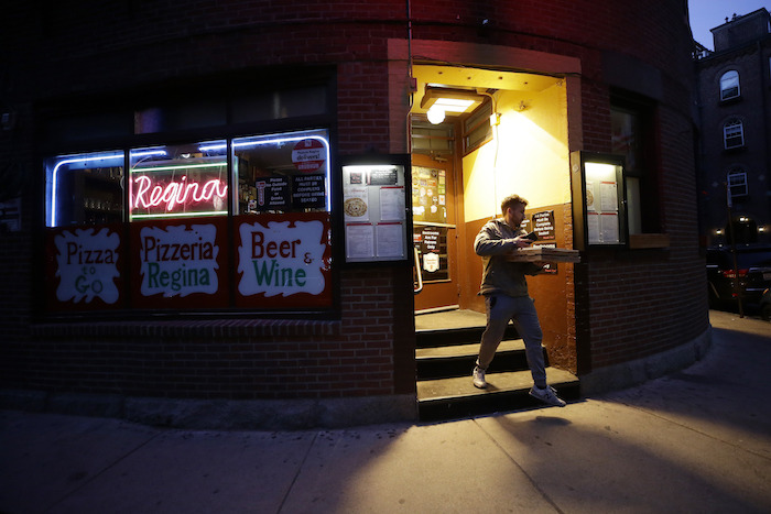 Un cliente sale de una pizzería en el barrio de North End, en Boston, el lunes 16 de marzo de 2020.