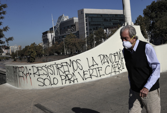 Un hombre usando una mascarilla pasa junto a un graffiti contra el presidente chileno Sebastián Piñera en medio de la pandemia del nuevo coronavirus en Santiago de Chile el lunes 6 de abril de 2020. Foto: Esteban Felix, AP