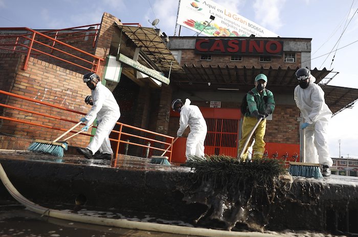 Soldados y trabajadores con trajes protectores limpian uno de los centros de distribución de alimentos más grandes de América Latina para contener la propagación del nuevo coronavirus en Bogotá, Colombia, el viernes 10 de abril de 2020.