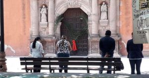 La iglesia de San Francisco colocó palmas en la puerta de la entrada porque no se abrió a los creyentes, pero se colocó una bocina al exterior para que los fieles escucharan la liturgia; afuera alrededor de 15 personas rezaron y prestaron atención. Foto: Pulso SLP. 