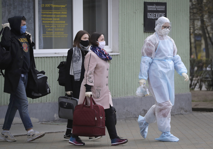 Una trabajadora sanitaria con un traje de protección acompaña a estudiantes hasta una ambulancia, en Minsk, Bielorrusia, el 21 de abril de 2020. 