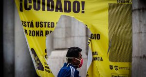 Un hombre camina detrás de un cartel señalatorío de las Zonas de Alto contagio de COVID-19. Foto: Andrea Murcia, Cuartoscuro