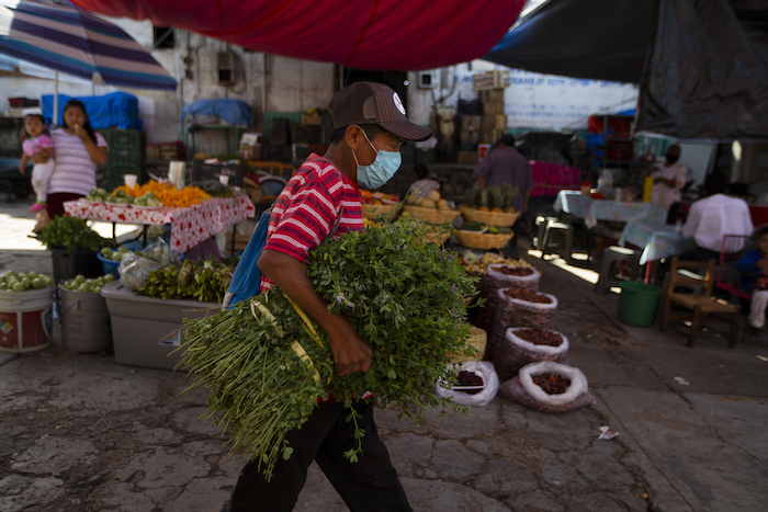 Un vendedor lleva cilantro bajo el brazo en el mercado de Acatlán de Osorio, México, para revenderlo en su comunidad, el 27 de junio de 2020. México depende desde hace años del dinero que envían los mexicanos que viven en el extranjero: las remesas suponen más divisas que la industria del petróleo y el turismo.