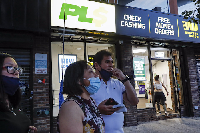 Magnolia Ortega (centro), en el exterior de una oficina de Western Union con su esposo, Arturo Morales, y su hija Marlene tras enviar dinero a su familia en México, el 24 de junio de 2020, en Staten Island, Nueva York. Ortega perdió su empleo limpiando casas por la pandemia del coronavirus, lo que redujo la cantidad de dinero que envía cada mes a su casa. Está considerando regresar a su pueblo natal, San Jerónimo Xayacatlán, pero dice que allí tampoco hay trabajo y eso significaría que un miembro menos de la familia envía remesas.