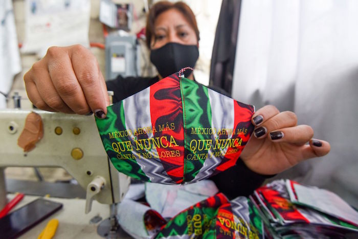 Una mujer muestra el cubrebocas patrio que ha elaborado en el Estado de México.