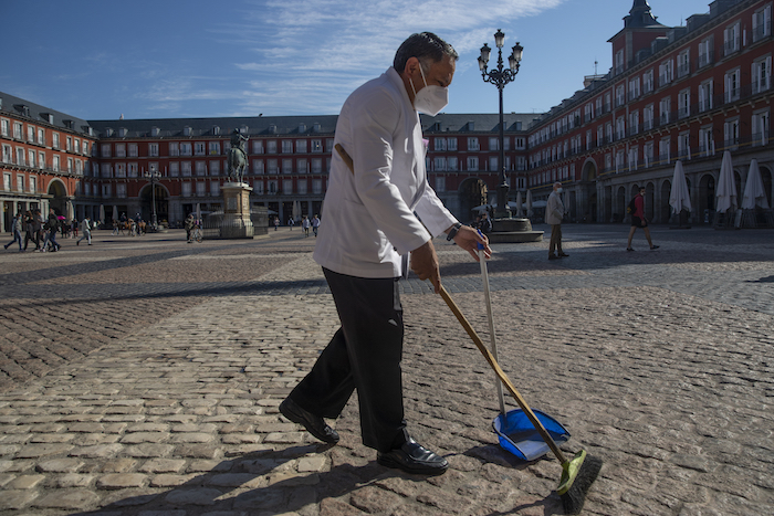 Un mesero porta una mascarilla para evitar la propagación del coronavirus mientras barre la terraza de un bar en el centro de Madrid, España, el viernes 9 de octubre de 2020. 