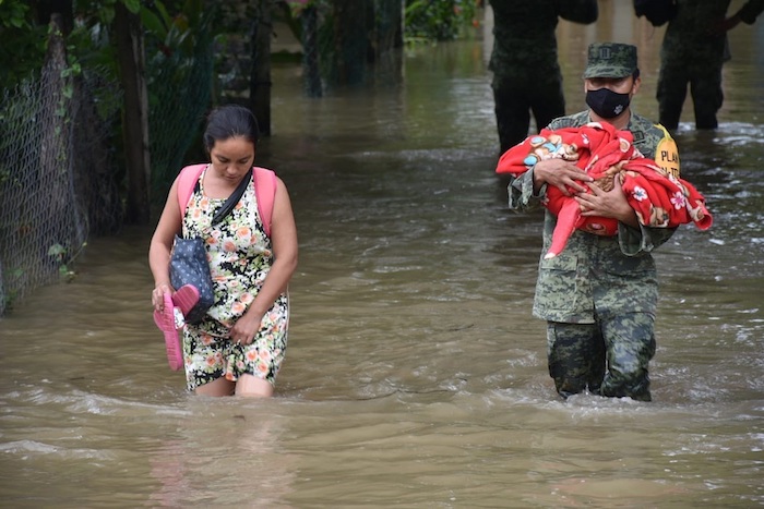 Fotografía cedida por Presidencia, que muestra a un miembro del Ejército mexicano mientras presta auxilio a una mujer y su hijo, durante las inundaciones en Nacajuca, en el estado de Tabasco (México).