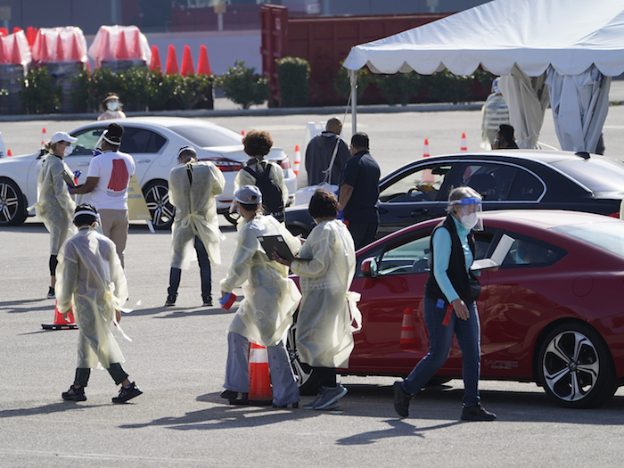 Personas aguardan dentro de sus vehículos en fila en un sitio de vacunación contra la COVID-19 fuera de The Forum en Inglewood, California, el martes 19 de enero de 2021.