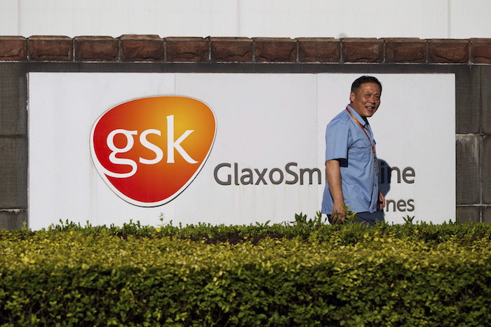 Un guardia de seguridad pasa junto al cartel de la farmacéutica británica GlaxoSmithKline (GSK).