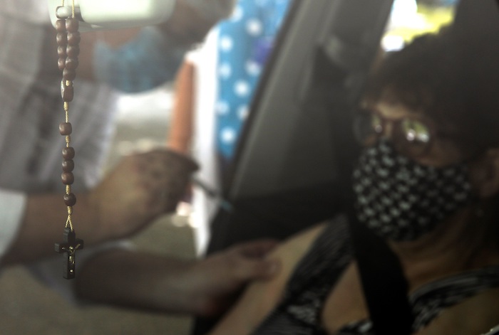 Fotografía a una camándula mientras una adulta mayor recibe una dosis de la vacuna CoronaVac contra la COVID-19 durante una jornada de vacunación para adultos mayores en un Drive-Thru, en Río de Janeiro (Brasil).