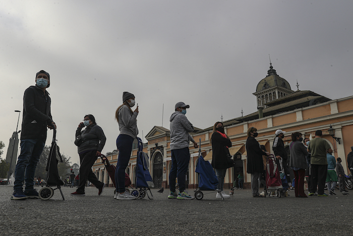 Varias personas permanecen en fila para comprar pescado para la Semana Santa en el mercado central en medio de la pandemia del coronavirus en Santiago de Chile, el jueves 1 de abril de 2021. La ciudad reimpuso restricciones a la movilidad para intentar contener un repunte de casos de COVID-19.