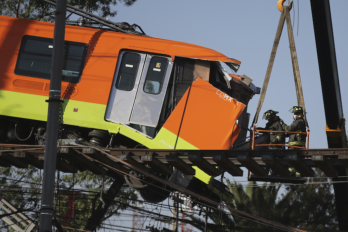 Bomberos trabajando para descolgar hasta el suelo un vagón de Metro que quedó suspendido en un tramo elevado del Metro, en Ciudad de México, el martes 4 de mayo de 2021.