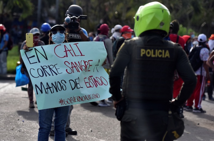 Una manifestante muestra un cartel a un policía durante unas protestas el 11 de mayo de 2021 en el barrio Siloé, en Cali (Colombia).