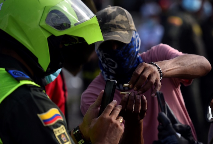 Un manifestante muestra unos cartuchos de bala a un policía durante unas protestas el 11 de mayo de 2021 en el barrio Siloé, en Cali (Colombia).