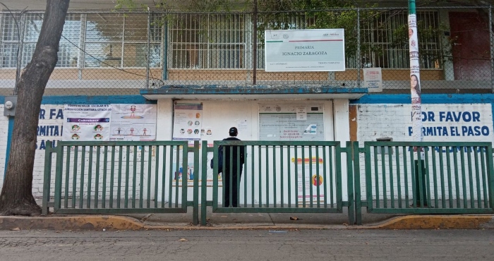 Una mujer se detiene a leer el comunicado emitido por la primaria Ignacio Zaragoza, en la Alcaldía Iztacalco. Este plantel decidió regresar hace 15 días a las clases presenciales.