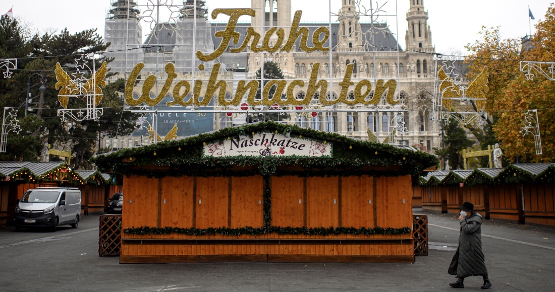 Una mujer camina por un mercado navideño cerrado frente al ayuntamiento de Viena.